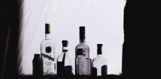 DRUNKO & WEDGIE four clear glass bottles in dim light