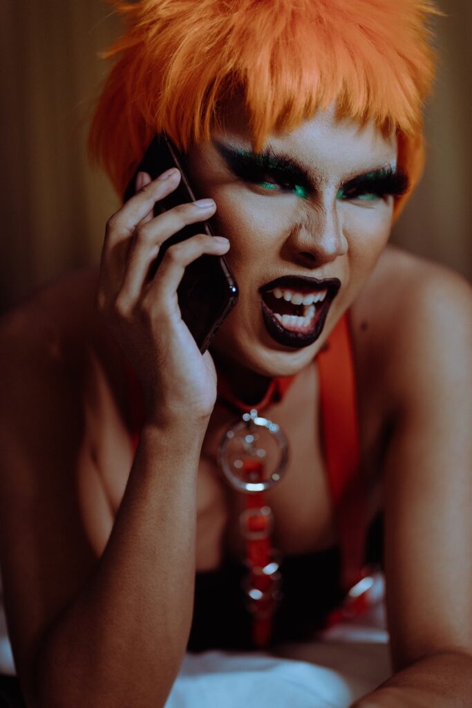 Angry young androgynous person shouting while talking on smartphone