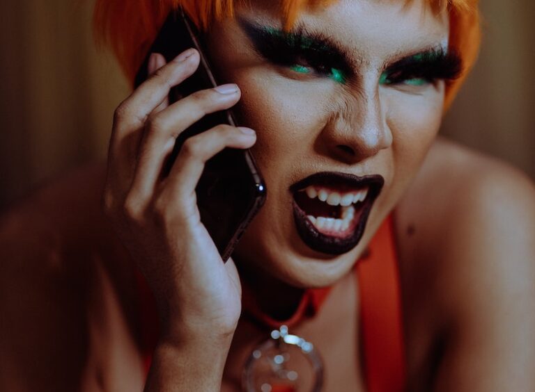Angry young androgynous person shouting while talking on smartphone